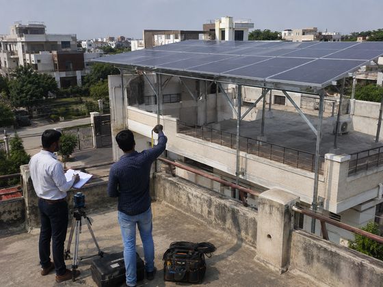 Engineers surveying a rooftop next to an installed solar array